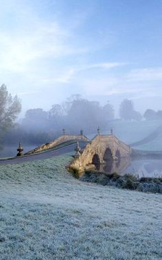 a foggy field with an old bridge in the distance