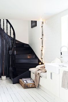 there is a black and white staircase in the house with lights on it's side