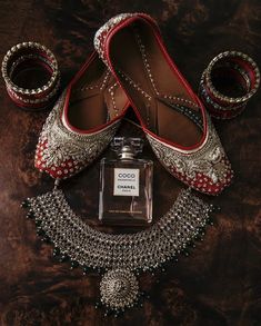 a pair of red shoes and a bottle of perfume on a table next to jewelry