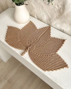 a white vase sitting on top of a wooden table next to a leaf shaped doily