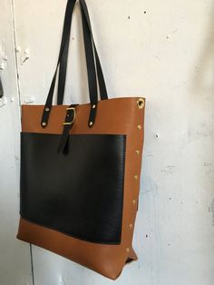 Constructed entirely from vegetable tanned leather and solid brass hardware, this tote is made with two exterior pockets and one interior removable wallet. Perfectly sized for a standard laptop this will get you through the day and the night with durability and style. Measures 14x15x4 with a removable adjustable cross body strap and over the shoulder handles. An adjustable closure means that it can change shape depending on how much or how little Lou are carrying. Modern Tote Shoulder Bag With Brass Hardware, Modern Everyday Satchel With Brass Hardware, Modern Satchel With Brass Hardware, Brown Leather Bag With Gunmetal Hardware, Everyday Tote Shoulder Bag With Brass Hardware, Brown Tote Bag With Brass Hardware, Brown Satchel With Brass Hardware Shaped As Tote, Brown Bags With Brass Hardware For Everyday, Brown Tote Satchel With Gunmetal Hardware