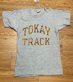 "This is a great 1980's vintage champion T-shirt. \"Tokay Track\" is screen printed in purple and yellow. from Lodi, California. It is in very good vintage condition. are they heavier weight than most vintage T-shirts but very soft!  Made in the USA. 88% cotton. 12% rayon. Single stitch. Label reads a size small. Based upon measurements most likely would fit an adult XS.  Measurements: Under arm to under arm: 15.5\" across Top back of collar to hem line: 24.5\" All sales are final. No returns ar Vintage College T-shirt With Lettering, Vintage Purple T-shirt With Letter Print, Vintage T-shirt With Lettering For College, Vintage Lettering T-shirt For College, Vintage Text Print Tops For Sports Events, Vintage Sports Tops With Text Print, Vintage Sports Top With Text Print, Vintage T-shirt With Screen Print For Sports Events, Vintage Sports T-shirt With Text Print