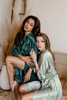 two women in green robes posing for the camera with their hands on each other's shoulders