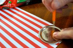 a person is painting the inside of a can with red and white stripes on it