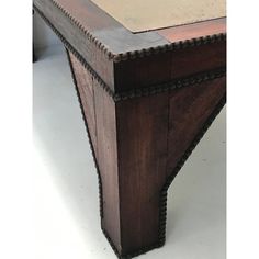 an old wooden table with metal trim around the edges and top, sitting on a white floor