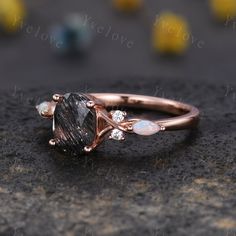 a rose gold ring with an oval shaped black diamond and two white diamonds on top