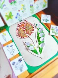 some paper flowers are sitting on top of a cutting board with other cards and magnets