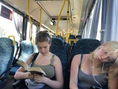 two women sitting on a bus reading books