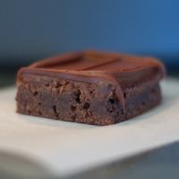 a piece of chocolate cake sitting on top of a white paper towel with a bite taken out of it