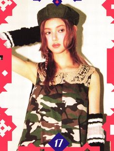 the girl is wearing camouflage clothing and holding her hat