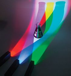 a rainbow colored vase sitting on top of a table next to some black wooden sticks