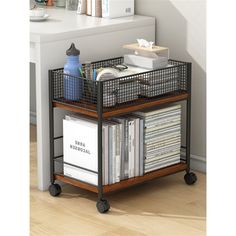 a metal and wood shelf with books on wheels in front of a white desk top