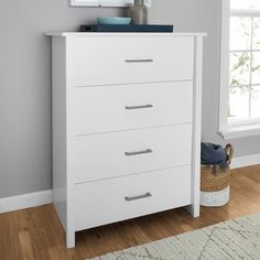 a white chest of drawers sitting on top of a wooden floor