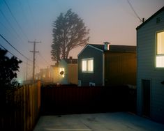 a foggy night in a neighborhood with houses and trees on the side of the street