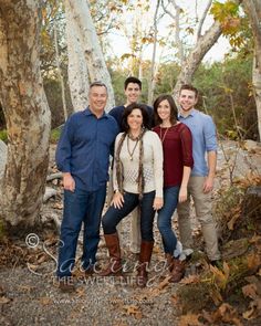 a group of people standing next to each other in front of some trees and leaves