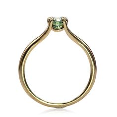 a yellow gold ring with a green diamond in the center, on a white background