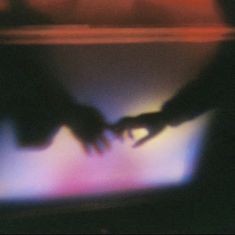 blurry image of two hands touching each other's fingers on a television screen