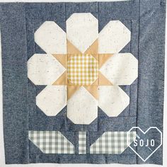 a blue and white quilted wall hanging with a patchwork flower on the center