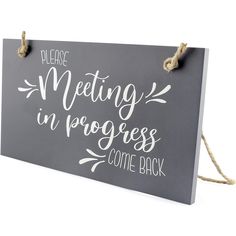 a sign that says please meeting in progress come back hanging from a rope on the wall