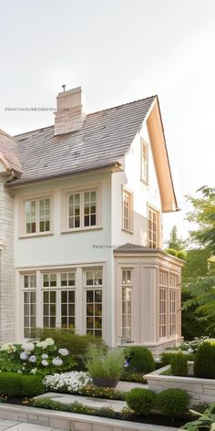 a large white house with lots of windows and landscaping around it's front yard