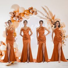 three women in orange dresses standing next to each other with balloons and decorations behind them