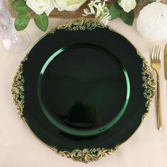 a green plate sitting on top of a table next to a knife and fork with white flowers in the background