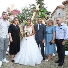 a group of people standing next to each other in front of a building and trees