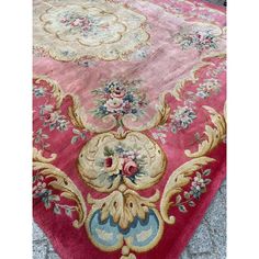 a pink rug with gold and blue flowers on it's sides, sitting on the ground