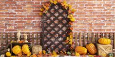 pumpkins and gourds are arranged in front of a brick wall with an iron screen