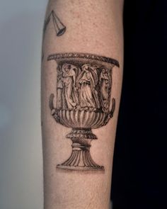 a black and white tattoo on the arm of a man with an ornate urn