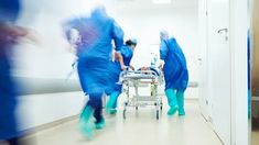 medical personnel in blue scrub suits walking down a hospital hallway