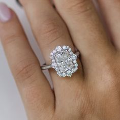 a woman's hand with a diamond ring on top of her finger and an oval shaped diamond in the middle