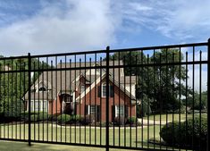 a red brick house behind a black fence