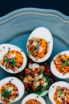 an overhead view of deviled eggs with various toppings on a blue platter