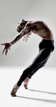 a shirtless male dancer in black and white poses with his arms stretched out to the side