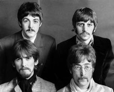 the beatles are posing for a portrait in black and white, with one man looking at the camera