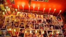 many candles are lit in front of pictures on the wall with people's faces