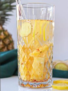 a glass filled with fruit and ice on top of a white table next to sliced lemons