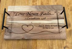 a wooden plaque with the words love never falls, and a heart on it's side