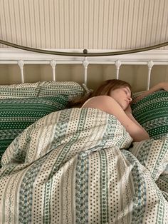 a woman laying in bed with her head on the pillow