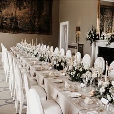 a long table set up with white chairs and place settings for an elegant wedding reception