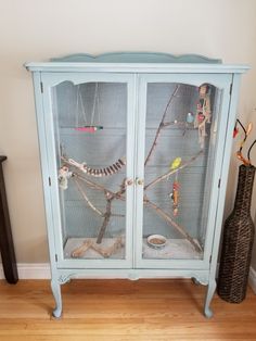 a birdcage with birds in it sitting on top of a wooden floor next to a vase