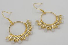 The earrings are made from a 1 inch gold circle that has gold beads and white crystal beads attached to the bottom half.  The total length of the earrings is 2 inches and each has a 10 K gold plated earring wire. White Round Earrings With Gold Beads, White Gold Beaded Round Earrings, Gold Beaded Round Metal Earrings, Round Metal Earrings With Gold Beads, Gold Dangle Hoop Earrings With Beads, Gold Hoop Earrings With Gold Beads, Handmade Small Hoop Gold Crystal Earrings, Handmade Gold Small Hoop Crystal Earrings, Gold Hoop Crystal Earrings Nickel-free