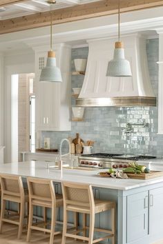 a kitchen with white cabinets and blue countertops is pictured in this image, there are four chairs at the center of the island