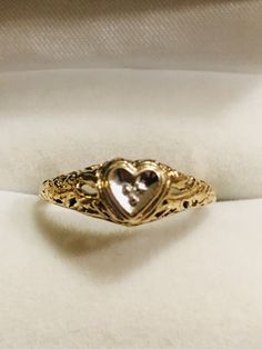 a heart shaped ring sitting on top of a white cloth covered cushioned pillow in a box