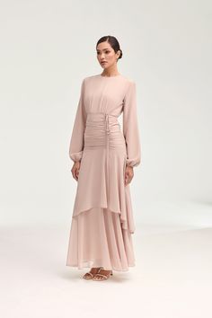 Introducing the Narjis Side Rouched Maxi Dress in Jasmine Pink. Embrace the exquisite side rouched detailing and asymmetrical tier design that flatters every figure. With elegant balloon sleeves and a flowy chiffon fabric, this dress is a timeless piece for any occasion. Elevate your wardrobe with this luxurious dress. Model is 5'7" and is wearing size XS/58". Modest Outfits Dresses, Date Outfit Ideas, Luxurious Dress, White Dress Formal, Nikkah Dress, Jasmine Dress, Luxurious Dresses, Soiree Dress, Date Outfit