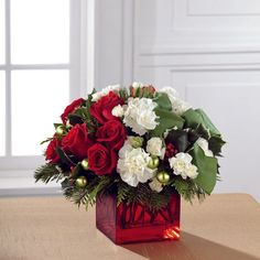 a red vase filled with white and red flowers