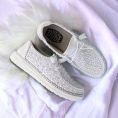 a pair of white shoes sitting on top of a bed