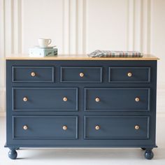 a blue dresser with gold knobs and a checkered napkin on the top drawer