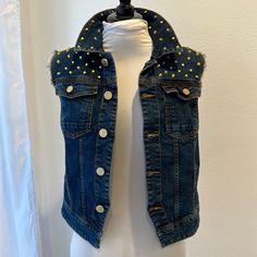 a white mannequin wearing a jean jacket with gold studs on the shoulders